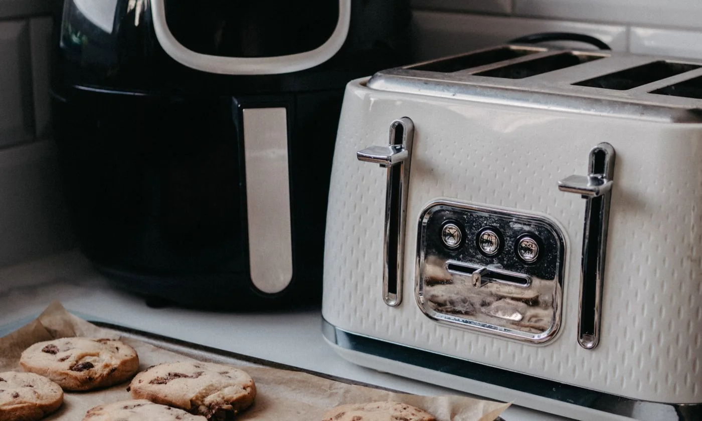 Baked cookies on a tray beside an air fryer and toaster