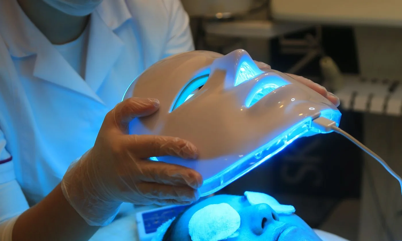 Beautician positioning an LED face mask during a facial treatment