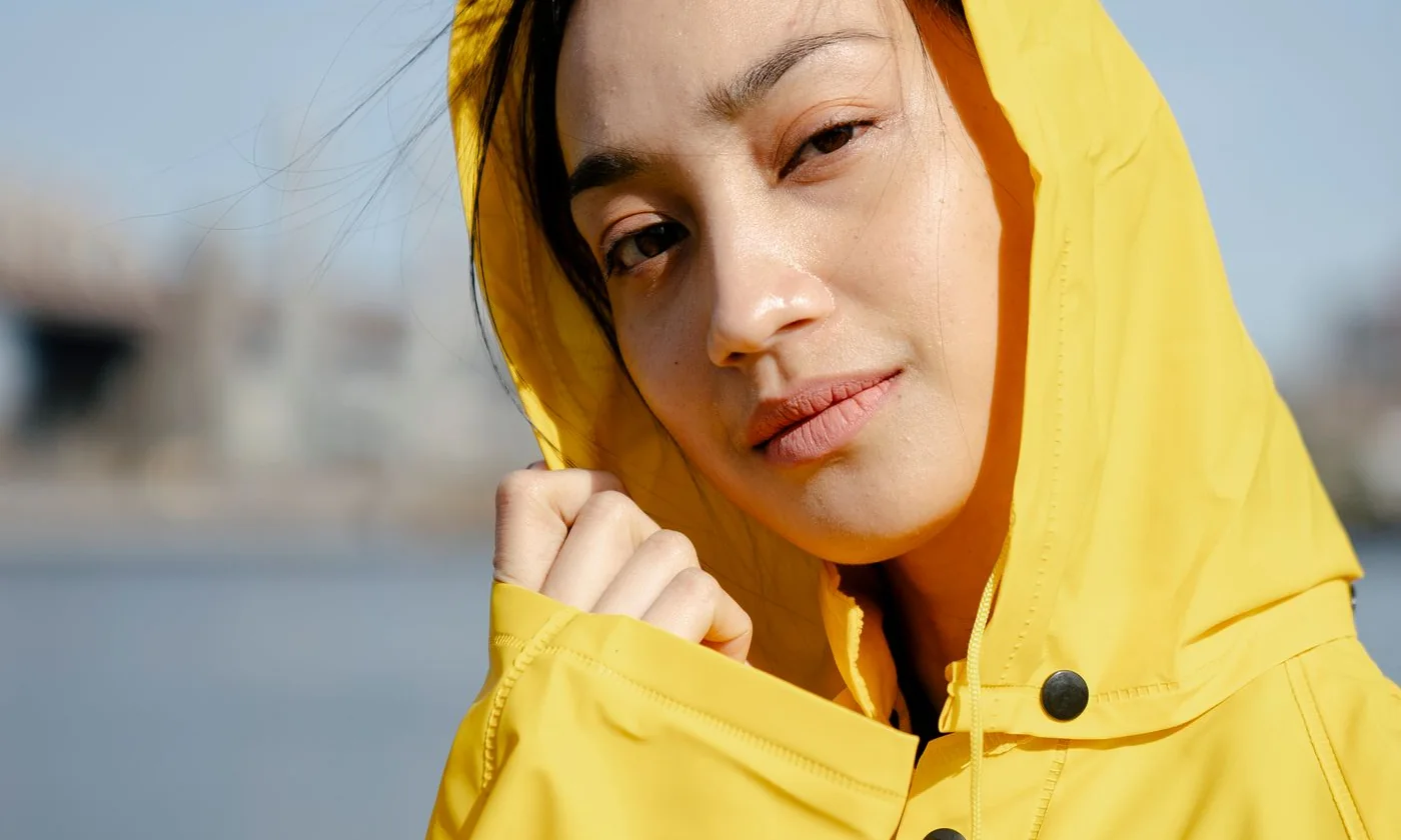 Woman wearing a yellow hooded raincoat outdoors