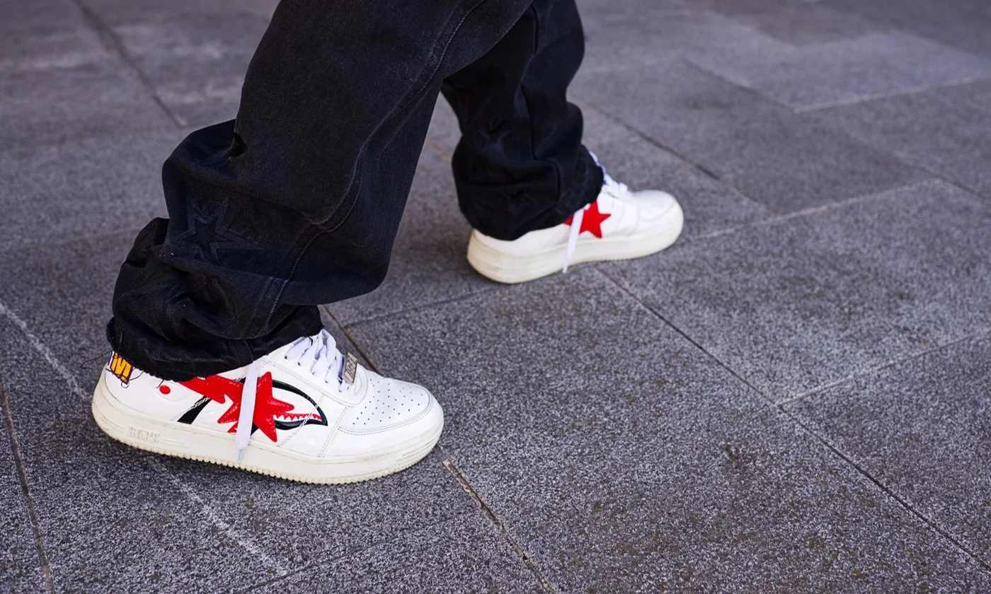 Close-up of white sneakers being worn on a paved street
